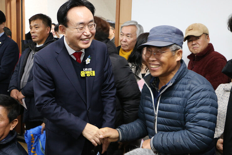 다도면 주민과의 대화 대화장 뒸쪽의 남성 주민과 악수를 하며 활짝 웃고 잇는 나주시장의 모습  남성 주민도 활짝 웃고 있는 모습