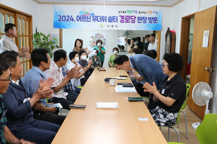 무더위 쉼터 현장 점검 나주시장이 인사말을 끝내고 자리에 앉아 있는 마을 어르신들께 허리굽혀 인사를 하고 있는 모습과 자리에 앉아 있는 마을 어르신들이 박수를 쳐 주고 있는 모습