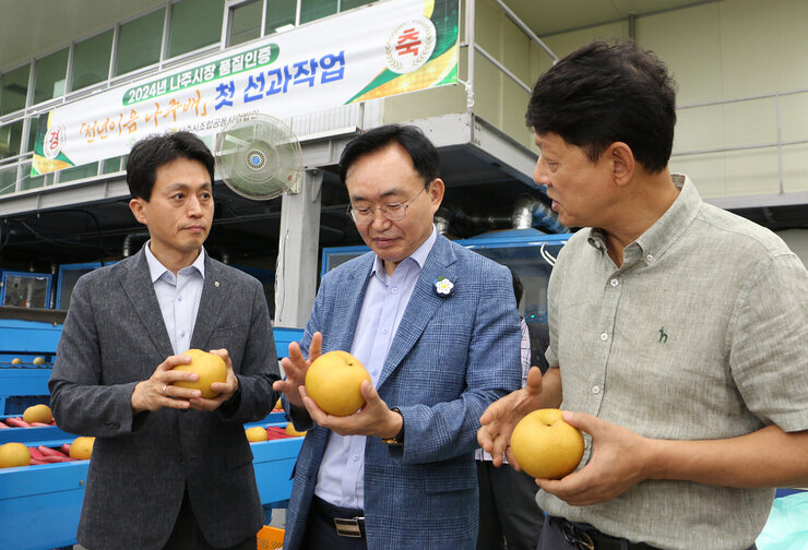 추석 명절 배 선과장 방문 나주시장과 농협나주시지부장 및 관계자가 한손으로 배르 들고 대화를 나누고 있는 모습