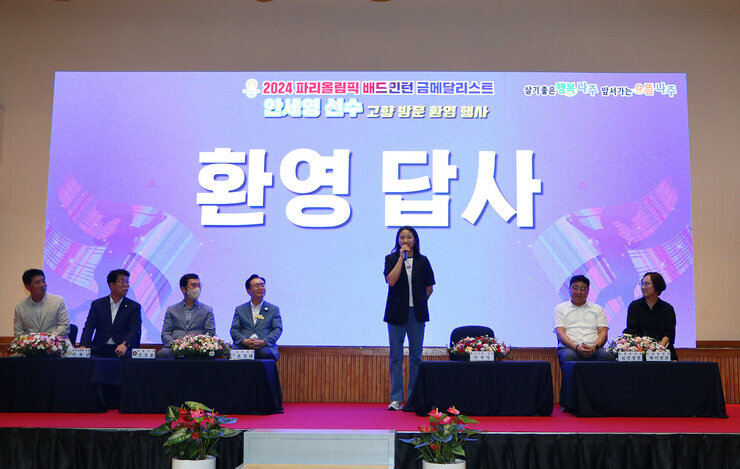 파리올림픽 금메달리스트 안세영 선수 나주 환영행사 안세영 선수의 환영 답사 모습 양 옆으로 국회의원 시장 및 부모가 앉아서 지켜보고 있는 모습