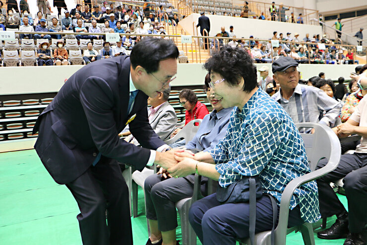 제28회 노인의 날 어르신 한마당 개막식 나주시장이 개막식장에 앉아 있는 여성 어르신과 두손을 잡으며 인사를 나누는 모습