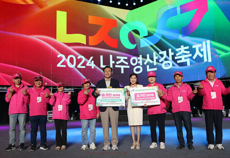 2024 나주영산강축제 개막식 나주시장과 송가인 가수, 송가인 팬카페 7명이 무대 위에서 쌀 기부 판넬을 들고 기념촬영을 하고 있는 모습