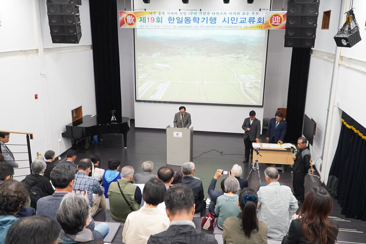 제19회 한일동학기행 시민교류회 나주시장의 축사모습과 참석자들이 자리에 앉아 있는 모습