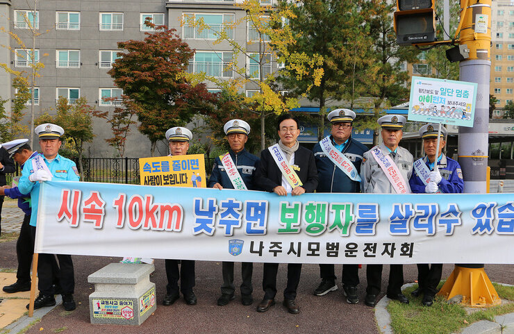 초등학교 등굣길 교통안전 캠페인 나주시장과 모범운자자회 회원 6명과 플래카드를 펼치고 기념촬영을 하고 있는 모습