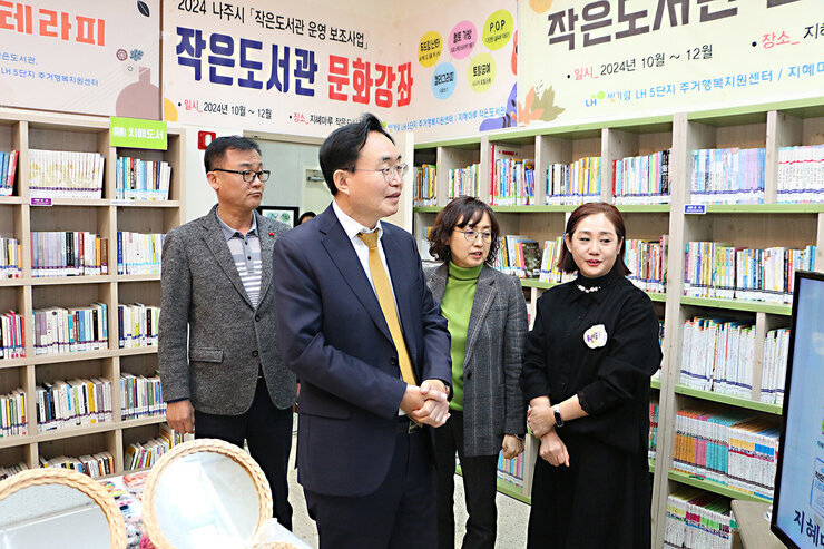 LH5단지 프로그램 성과나눔 전시회 나주시장이 LH5단지 도서관의 프로그램에 대해  관계자의 설명을 듣고 있는 모습