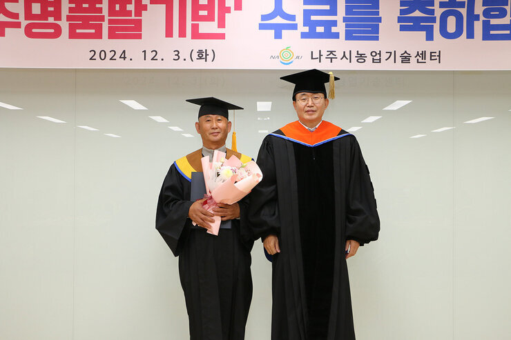 친환경농업대학 명품딸기반 수료식 나주시장과 공로패를 받은 수료생이 기념촬영을 하고 있는 모습