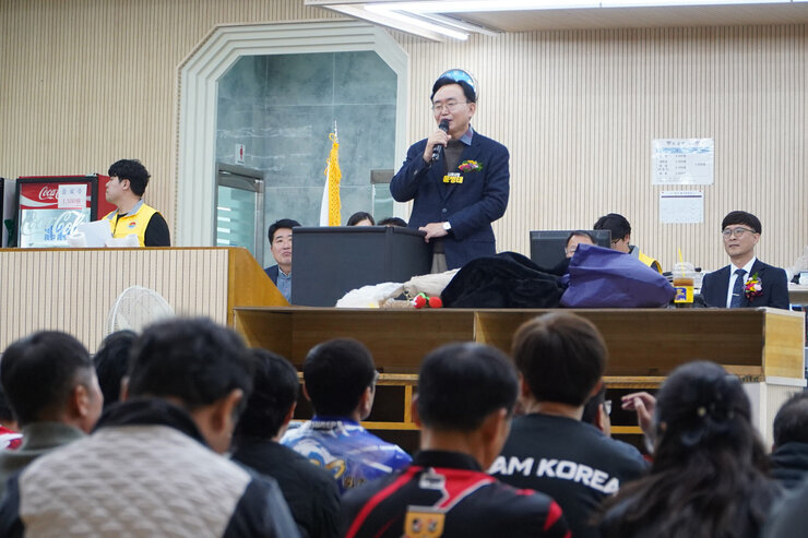   윤병태 나주시장이 무대 위에 올라 연설하고 있고, 많은 관람객들이 바닥에 앉아 연설자를 바라보고 있는 볼링장 내부 전경