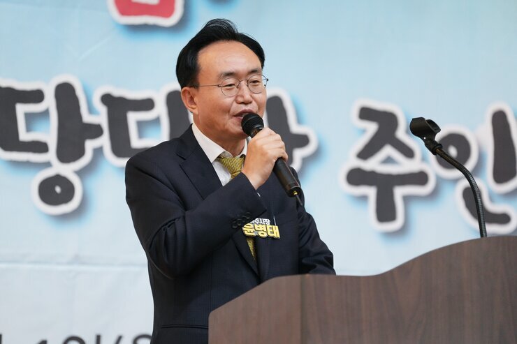  나주 시장(윤병태)이 단상 앞에서 마이크를 잡고 연설하며 미소 짓고 있는 클로즈업 사진