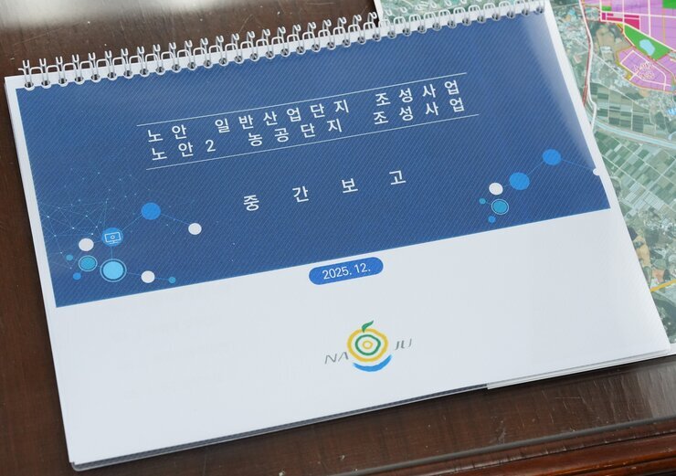  '노안 일반산업단지 조성사업 노안2 농공단지 조성사업 중간보고 2025. 12.' 날짜가 표시된 스프링 달력의 표지 클로즈업 사진. 표지 하단에는 나주시 로고가 있다.