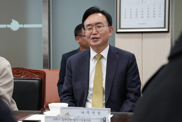  나주시장 명패가 놓인 테이블에 앉아 미소를 짓고 있는 윤병태 나주시장의 클로즈업 사진.