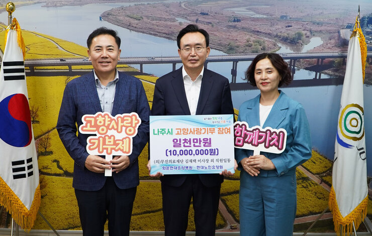 나주시 고향사랑기부 참여 일천만원(10,000,000원) 팻말을 든 시장님과 고향사랑 기부제 팻말을 든 남성과  함께가치 팻말을 든 여성 세 명이 기념촬영 중이다.