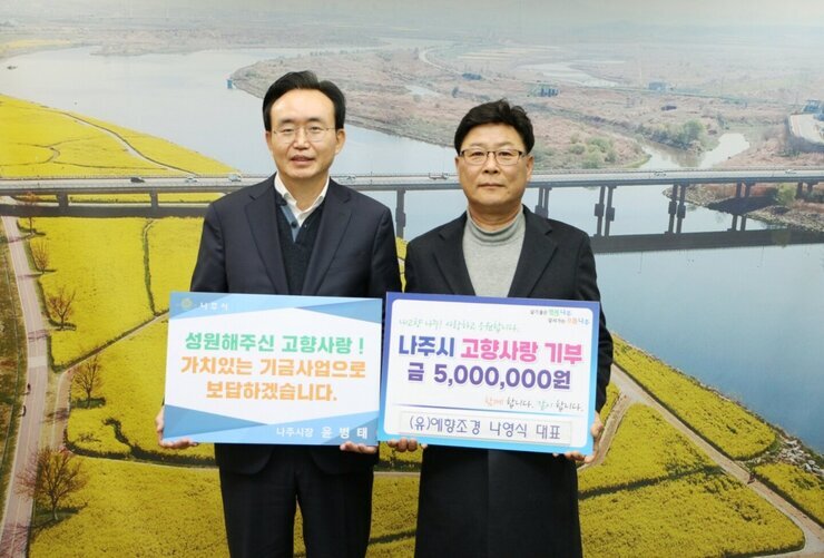 왼쪽에 시장님이 성원해주신 고향사랑! 가치있는 기금사업으로 보답하겠습니다. 라고 적힌 팻말을 들고 오른쪽에 나주시 고향사랑 기부 금 5,000,000원 (유)예향조경 나영식 대표라고 적힌 팻말을 들고 기념 촬영 중이다