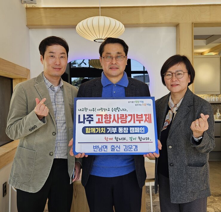   살기좋은 행복 나주 앞서가는 으뜸 나주 내고향 나주! 사랑하고 응원합니다. 나주시 고향사랑 기부 금 5,000,000원 함께 합니다. 같이 합니다.  반남면 출신 김문겸 이라고 적힌 팻말을 들고 있는 김문겸과 베이지 색 자켓을 입고 있는 남성, 회색 자켓을 입고있는 여성이 손하트를 하고 있다