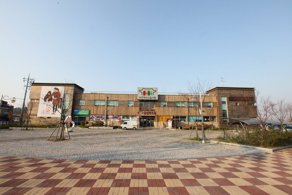 나주목사고을시장 전경을 찍은 사진. 총 2층으로 되어 있는 시장이며 중간과 왼쪽 오른쪽에 각각 하나씩 입구가 있고 그 앞으로 보도블럭이 깔려 있음.