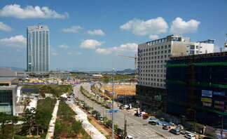 도로를 중점으로 오른쪽에는 공사중인 건물과 왼쪽에는 고층 건물이 보인다