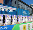 나주쌀 새청무 뉴질랜드 첫 수출 상차식 측면에서 촬영한 나주통합RPC 앞에 놓인 10키로짜리 새청무 나주쌀14포대 모습과 뒷편에 대형트럭에 뉴질랜드 첫 수출이라는 플래카드가  부착되어 있는 모습