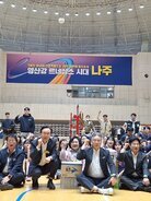 나주시배구협회장배 고등학교 남녀 배구대회 나주시장과 배구협회장 및 내빈들이  배구 코트 바닥에 앉아서 한손을 올리고 화이팅을 외치며 기념촬영을 하고 있는 모습