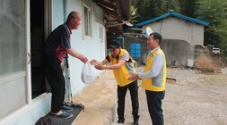 공손히 할아버지에게 반찬을 전달하는 봉사자와 눈을 마주치며 대화하는 봉사자