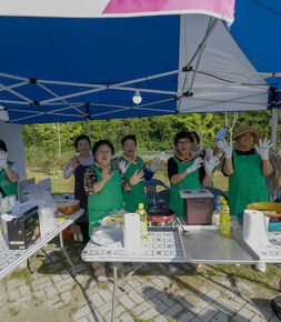 천막아래에서 음식준비를 하며 율동과 함께 음악회를 즐기고있는 봉사자들