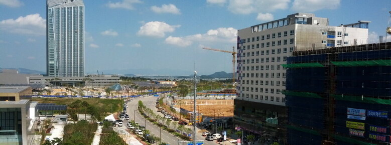 도로를 중점으로 오른쪽에는 공사중인 건물과 왼쪽에는 고층 건물이 보인다