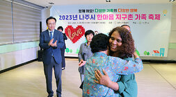 나주시 한마음 지구촌 기족 축제 시상자 중 여성 한명이 가족분과 포옹을 하고 있고 나주시장이 뒤에서 박수를 쳐 주고 있는 모습
