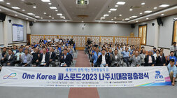 One Korea 피스로드 2023 전남 나주시 통일대장정 출정식 플랭카드를 앞에 두고 참여자들이 앉아서 기념촬영을 하고 있는 모습