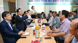 세지면 무더위 쉼터 방문 자리에 앉아서 나주시장이 남성 어르신의 질문에 팔을 들어올리며 설명을 하고 있는 모습
