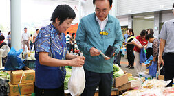 추석 명절맞이 공산5일시장 장보기 행사 나주시장이 건어물을 판매하는 여성 상인에게 구매한 물품에 대해 나주사랑상품권을 들고 있는 모습