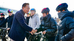  윤병태 나주시장이 자전거 헬멧과 운동복을 착용한 사이클리스트와 야외에서 악수를 나누며 미소 짓고 있다.