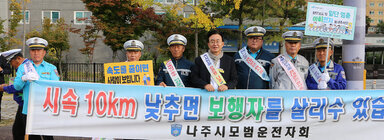 초등학교 등굣길 교통안전 캠페인 나주시장과 모범운자자회 회원 6명과 플래카드를 펼치고 기념촬영을 하고 있는 모습