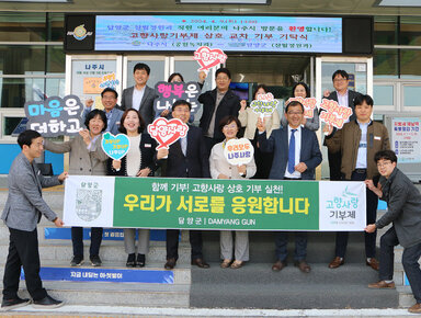 고향사랑 기부 상호 교차 기탁식 나주시 부시장과 공원녹지과장 및 직원, 담양군 산림정원과장 및 직원들이 담양군 플래카드를 펼치고 기념촬영을 하고 있는 모습