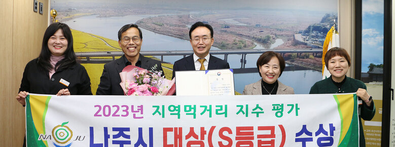 2023년 지역먹거리 지수 평가 대상 수상 나주시장과 농업기술센터 소장, 담당과장, 담당 팀장 및 직원이 플래카드를 펼치고 기념촬영을 하고 있는 모습