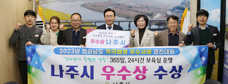 나주시장과 행정복지국장, 담당부서 과장 및  직원들이 전라남도 적극행정 우수사례 경진대회 나주시 우수상 수상  관련 플래카드를 펼치고 화이팅을 하며 기념촬영을 하고 있는 모습