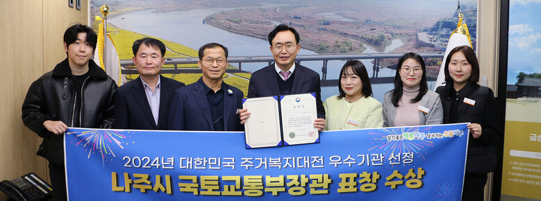 주거복지대전 우수기관 나주시 국토부장관 표창  나주시장과 담당부서 직원들이 플래카드를 펼치고 기념촬영을 하고 있는 모습