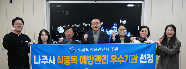  윤병태 나주시장(가운데)과 시청 직원들로 보이는 남녀 7명이 '식품의약품안전처 주관 나주시 식중독 예방관리 우수기관 선정 나주시'이라고 적힌 파란색 현수막을 들고 기념사진을 찍고 있는 모습. 모두 주먹을 쥐고 있다.