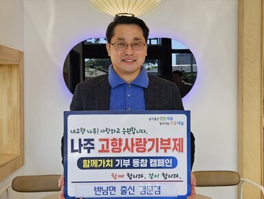  살기좋은 행복 나주 앞서가는 으뜸 나주 내고향 나주! 사랑하고 응원합니다. 나주시 고향사랑 기부 금 5,000,000원 함께 합니다. 같이 합니다.  반남면 출신 김문겸 이라고 적힌 팻말을 들고 있는 김문겸
