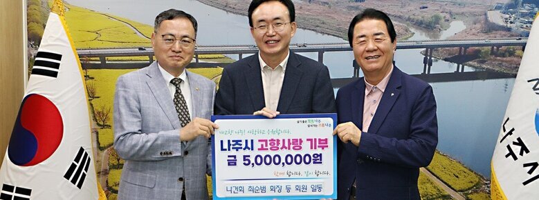 살기좋은 행복 나주 앞서가는 으뜸 나주 내고향 나주! 사랑하고 응원합니다. 나주시 고향사랑 기부 금 5,000,000원 함께 합니다. 같이 합니다. 나건회 최순범 회장 등 회원 일동이라고 적힌 팻말을 들고 있는 윤병태 시장과 중년 남성 2명