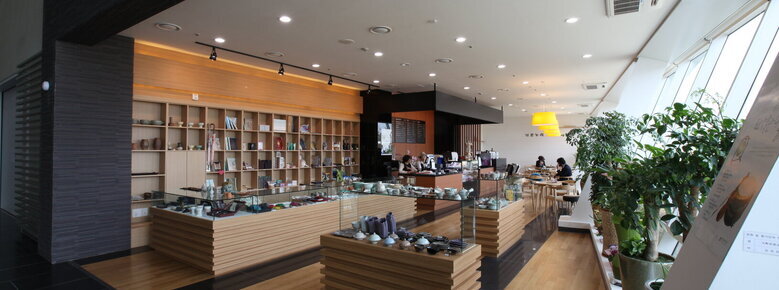 나주국립박물관 내부에 있는 카페와 기념품점을 찍은 사진. 카페에 사람들이 차를 마시고 있고 그 앞으로 여러가지 도자기들이 전시되어 있음.