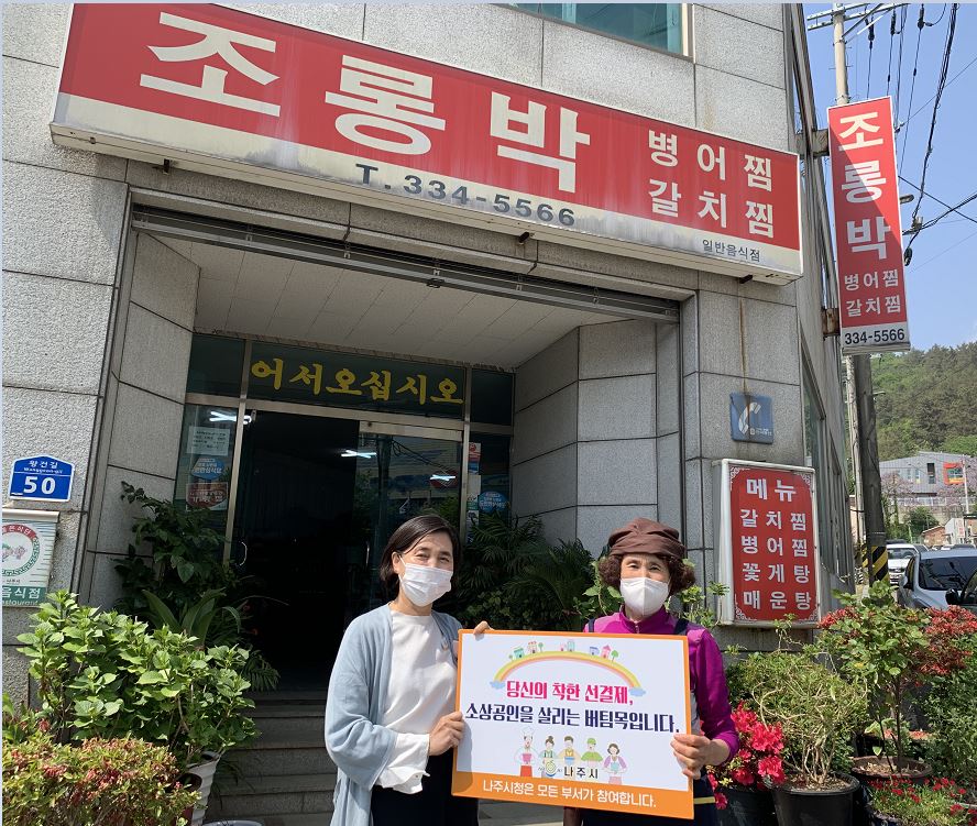 선결제 캠페인 안내판을들고 가게정문앞에서 촬영한 사진