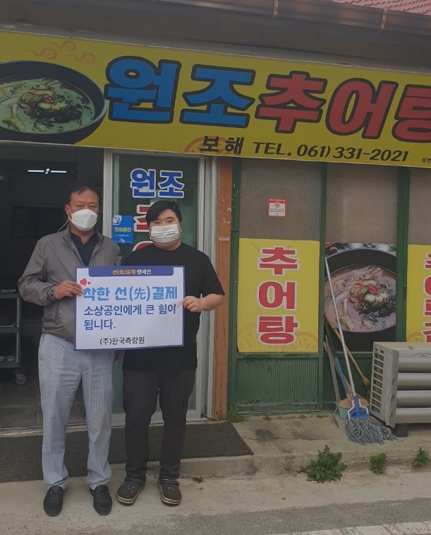 선결제 캠페인 안내판을들고 가게정문앞에서 촬영한 사진