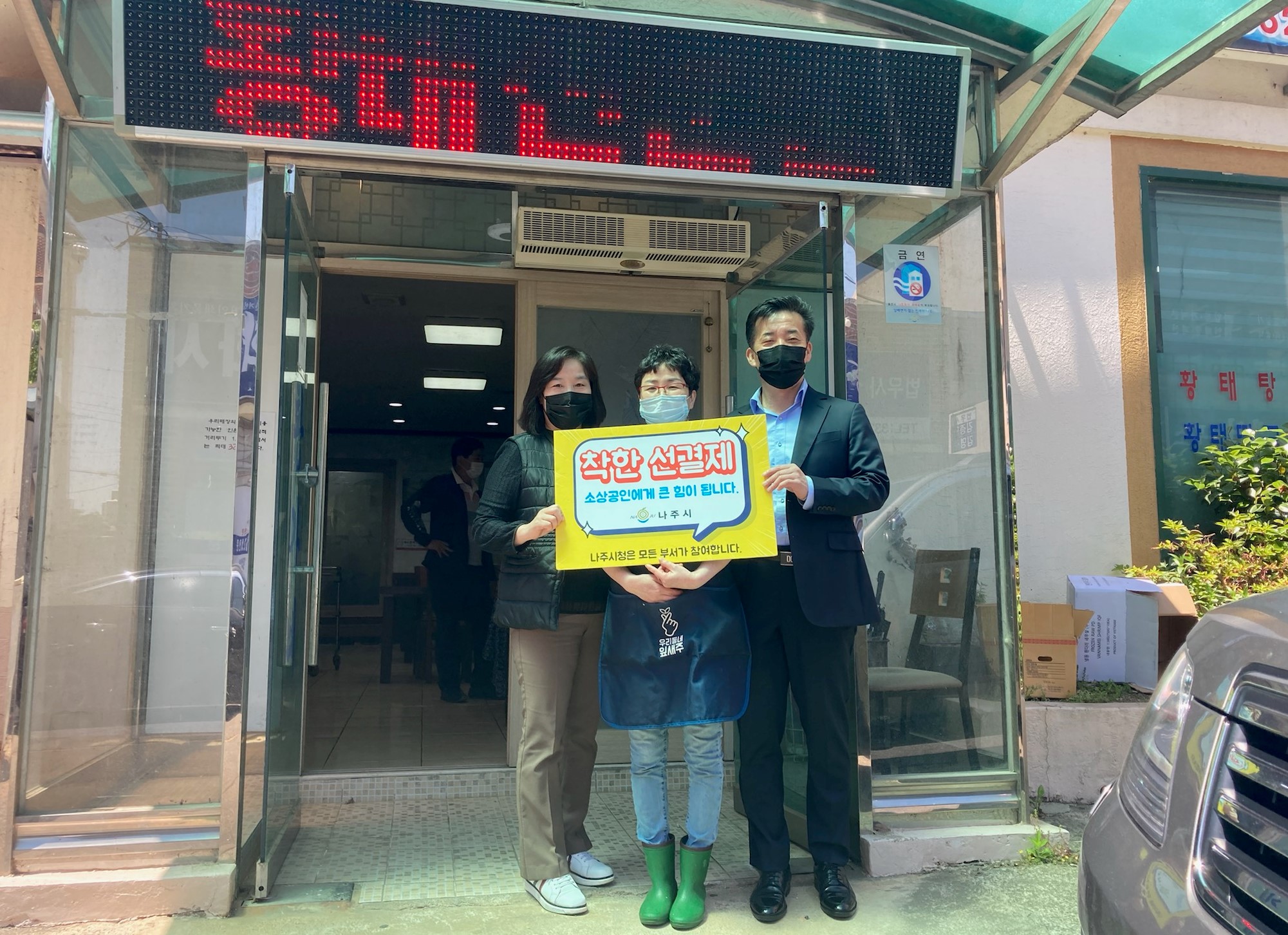 선결제 캠페인 안내판을들고 가게정문앞에서 촬영한 사진